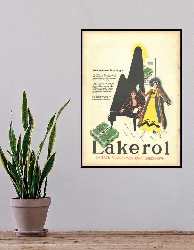 En hvid væg med en plante foran. på væggen hænger en plakat. På plakaten er en original reklame plakat for Läkerol, hvor en kvinde og en pianist spiller musik. plakaten er gul og klaveret er sort.