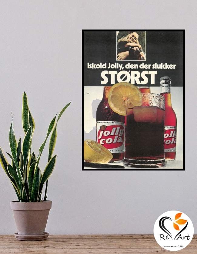 Dette er en hvid væg med en plakat på. Dette er en original reklame plakat fra jolly cola. På plakaten er der jolly colaer og et glas med en iskold cola. Plakaten er sort og hvid, og der også citroner. Derudover er der en plante foran væggen.